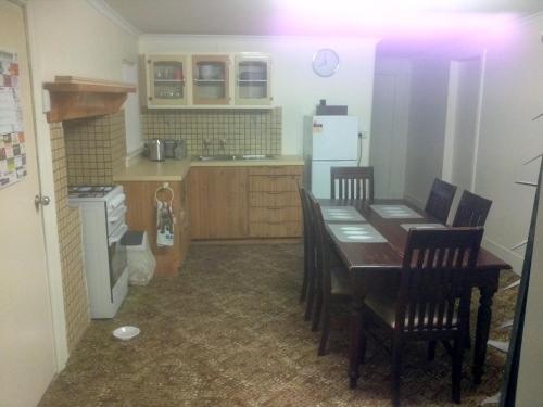 cocina con mesa, sillas y nevera en Migga Cottage, en Winkie
