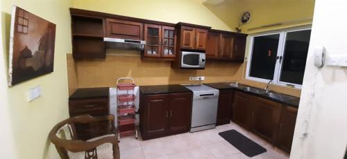 a small kitchen with wooden cabinets and a microwave at Rudra Residence Apartment in Colombo
