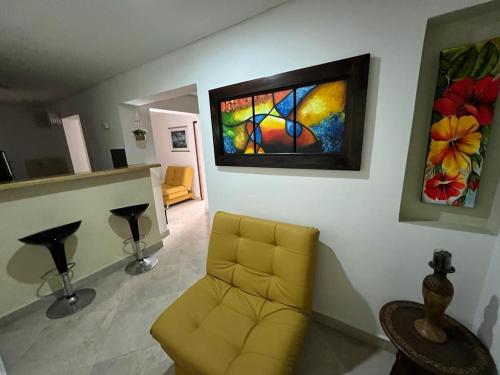 a living room with a yellow chair and a painting on the wall at Apartamento Amoblado laureles estadio in Medellín