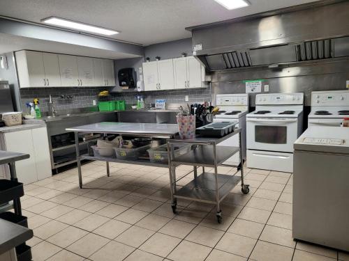 eine Küche mit weißen Geräten und einem Tisch darin in der Unterkunft Banff International Hostel in Banff