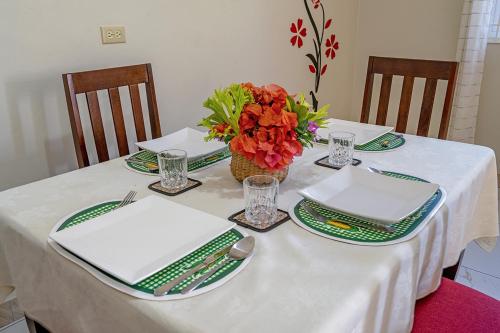 a table with green and white plates and a vase of flowers at Palm Leaf Cottage in Montego Bay
