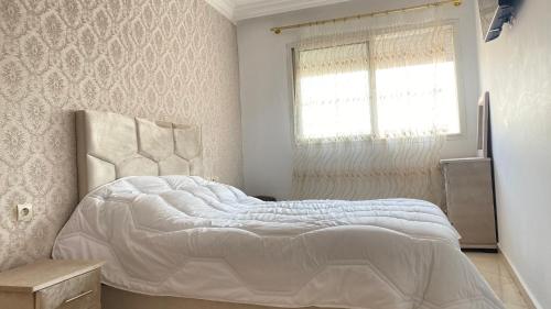 a bedroom with a white bed with a window at loubna 3 in Rabat