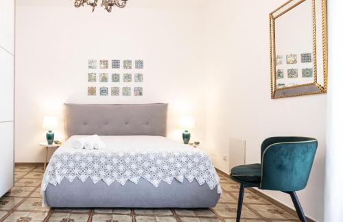 - une chambre avec un lit, une chaise et un miroir dans l'établissement Bellavista apartment, à Caltagirone