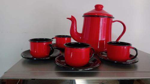 cuatro tazas de café rojas y una jarra roja en un estante en Em Busca Hostel en Bonito