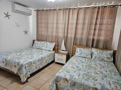 - une chambre avec 2 lits et une fenêtre avec des rideaux dans l'établissement Combate Whitehouse, Playa Combate, Cabo Rojo, à Cabo Rojo