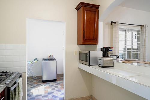 a kitchen with a counter top with a microwave and a refrigerator at Palm Leaf Cottage in Montego Bay