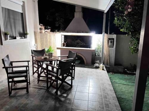 un patio con mesa, sillas y chimenea en Ευχάριστο εξοχικό σπίτι!, en AgiaKampos
