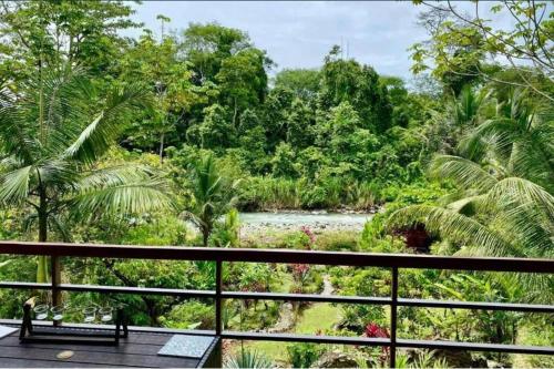 a balcony with a view of a river and trees at Sloth Premium Riverfront Jungle Villa with Jacuzzi and Pool in Uvita