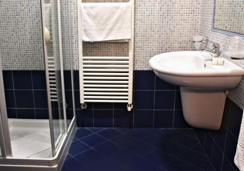 uma casa de banho em azulejos azuis com um lavatório e um chuveiro em Appartamento Ghalà em Galatone
