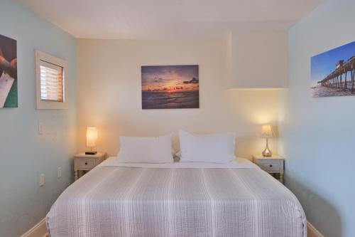 a bedroom with a white bed with two lamps at Longboard in Holmes Beach