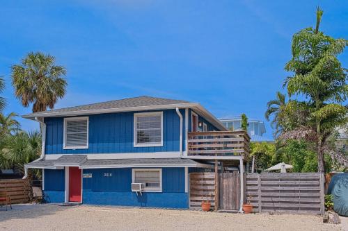 a blue house on the beach with palm trees at Longboard in Holmes Beach