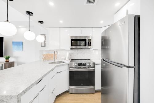 a kitchen with white cabinets and a stainless steel refrigerator at Marina Views Studio - Ilikai, 941 in Honolulu