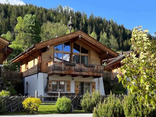 a large wooden house with a balcony at Premium chalet with sauna on a sunny slope in Wald im Pinzgau