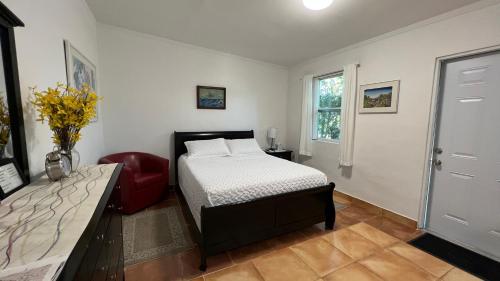 a bedroom with a bed and a red chair at Cozy Rooms in Homestead