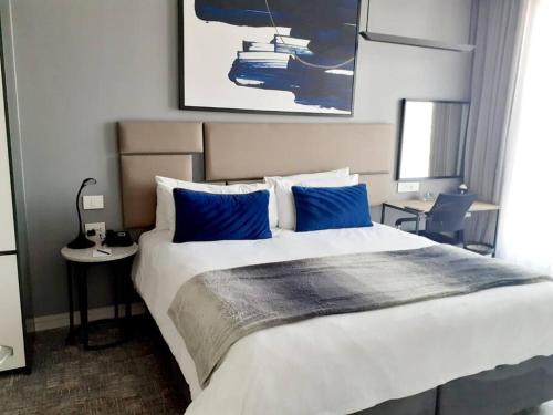 a bedroom with a large bed with blue pillows at 530 on the Parks in Johannesburg