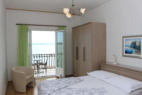 une chambre avec un lit et une chaise et un balcon dans l'établissement Apartments by the sea Podgora, Makarska - 21378, à Podgora
