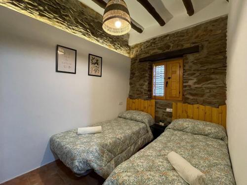 a bedroom with two beds and a stone wall at Rural House Adra near Beaches & Views in Las Hoyas del Barranco