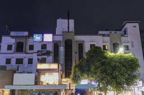 um edifício branco alto com uma árvore em frente em Super Collection O Planet Grande By Elite Hospitality em Chennai