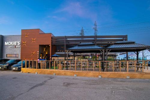 a building with a restaurant with tables and umbrellas at Sandman Hotel Hamilton in Hamilton