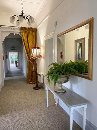 a hallway with a table and a mirror and a lamp at Bavaria Boutique Hotel in Auckland