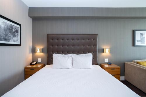 a bedroom with a large bed and a couch at Sandman Hotel Hamilton in Hamilton