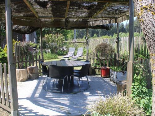 un patio con mesa y sillas bajo una pérgola en Cottage Oree des bois in Paliseul with Garden, en Paliseul