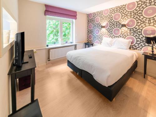 una camera con letto e TV di Luxurious holiday home on the banks of the Ourthe a Barvaux-sur-Ourthe