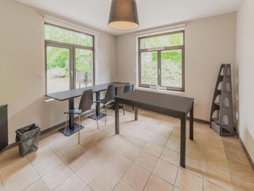 a dining room with two tables and chairs and windows at Spacious Villa Near Barvaux in Barvaux