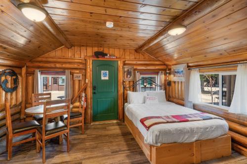a bedroom in a log cabin with a bed and a desk at The Bucking Moose in West Yellowstone
