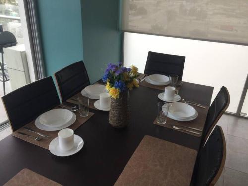 a dining room table with plates and a vase of flowers at Dep. Salinas, Chipipe. in Salinas