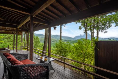 a deck with chairs and a view of mountains at Kusayane no yado Ryunohige in Yufu