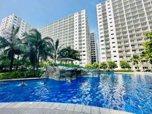 a large swimming pool in front of tall buildings at 1 bedroom unit condo in Manila