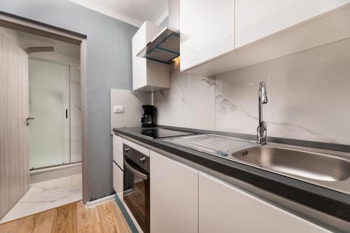 una cocina con armarios blancos y fregadero en Apartments Vugrin en Šilo