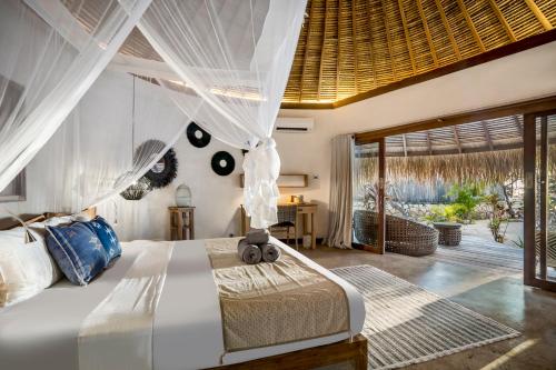 um quarto com uma cama branca e uma grande janela em Seed Resort em Nembrala