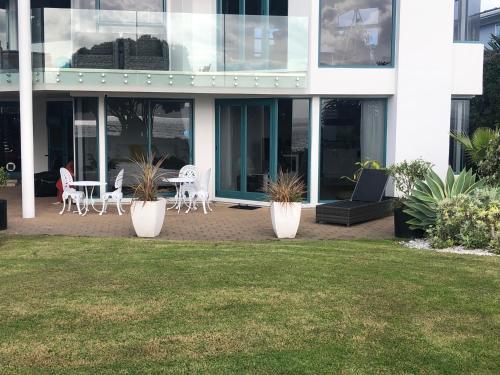 a building with chairs and tables in front of it at Luxury Waterfront in One Tree Point