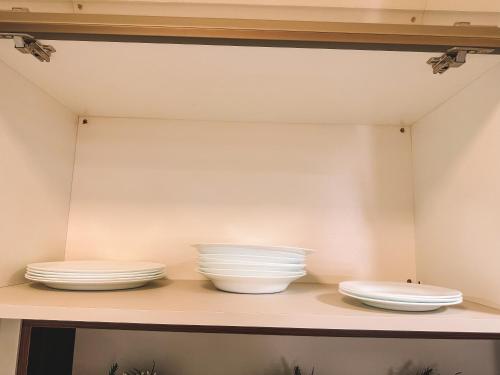 three bowls and plates sitting on a shelf at Apto a 3 minutos da Rua Coberta de Gramado in Gramado