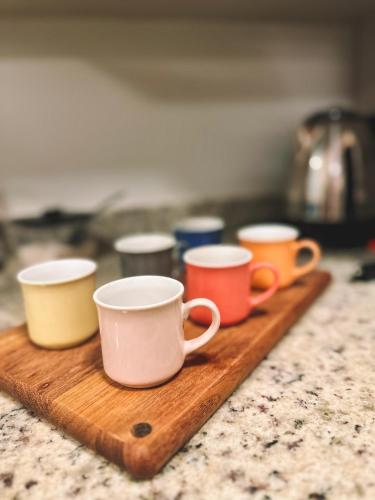four coffee cups sitting on a wooden cutting board at Apto a 3 minutos da Rua Coberta de Gramado in Gramado