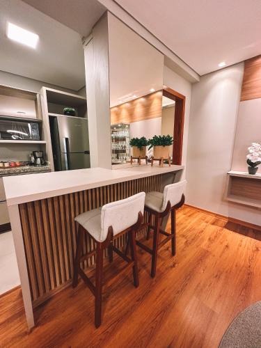a kitchen with a bar with chairs and a counter at Apto a 3 minutos da Rua Coberta de Gramado in Gramado