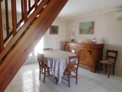 une salle à manger avec une table et des chaises et un escalier dans l'établissement Maison spacieuse 9 pers, proche plage, jardin, animaux acceptés sur demande - FR-1-476-201, à La Faute-sur-Mer