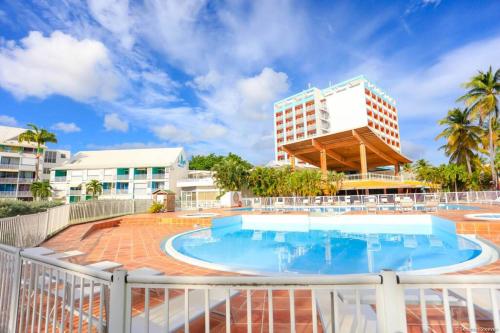 a resort pool with a building in the background at Paradis studio & plage à 1 min in Le Gosier
