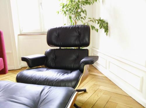 a black leather chair in a room with a plant at Basel Charme Apartments in Basel