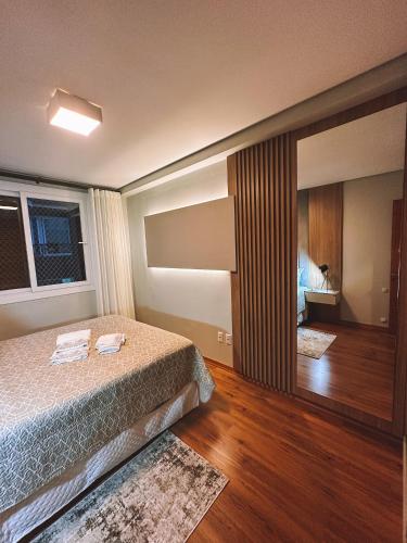 a bedroom with a bed and a large mirror at Apto a 3 minutos da Rua Coberta de Gramado in Gramado