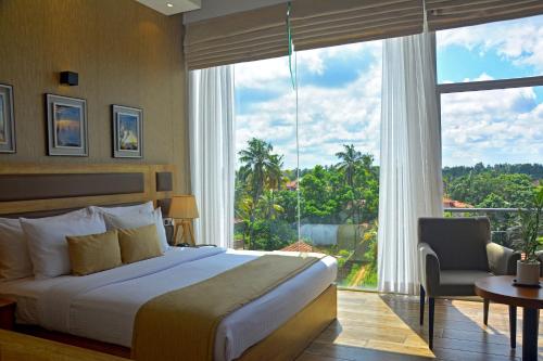 ネゴンボにあるBelmont Boutique Hotelのベッドと大きな窓が備わるホテルルームです。