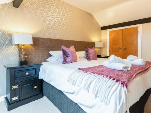 a bedroom with a large bed with purple and white pillows at Ty Bach Twt in Dyffryn