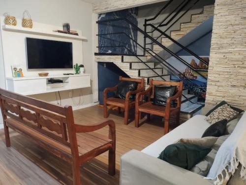 a living room with a couch and chairs and a staircase at Casa Espaço Pérola in Rio das Ostras