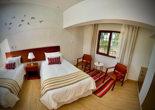 a bedroom with two beds and chairs and birds on the wall at Inkantari Boutique Hotel in Cusco