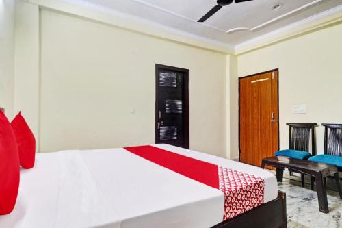 - une chambre dotée d'un lit blanc avec des oreillers rouges et bleus dans l'établissement Flagship Hotel Moonshine Inn, à New Delhi