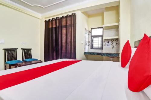 - une chambre avec un grand lit blanc et des oreillers rouges dans l'établissement Flagship Hotel Moonshine Inn, à New Delhi