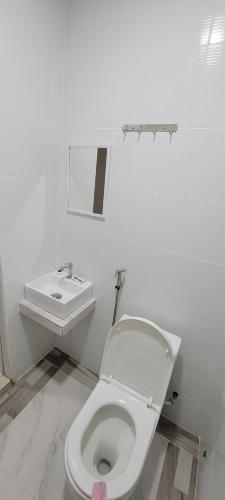 a white bathroom with a toilet and a sink at HOTEL SHAFURA 3 in Cukai