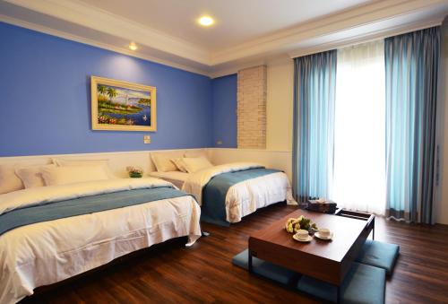 2 camas en una habitación con paredes azules en Yunju House, en Jiaoxi